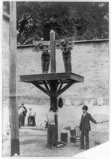 Prisoners in pillory,tied to whipping post,man whit whip,prison,De